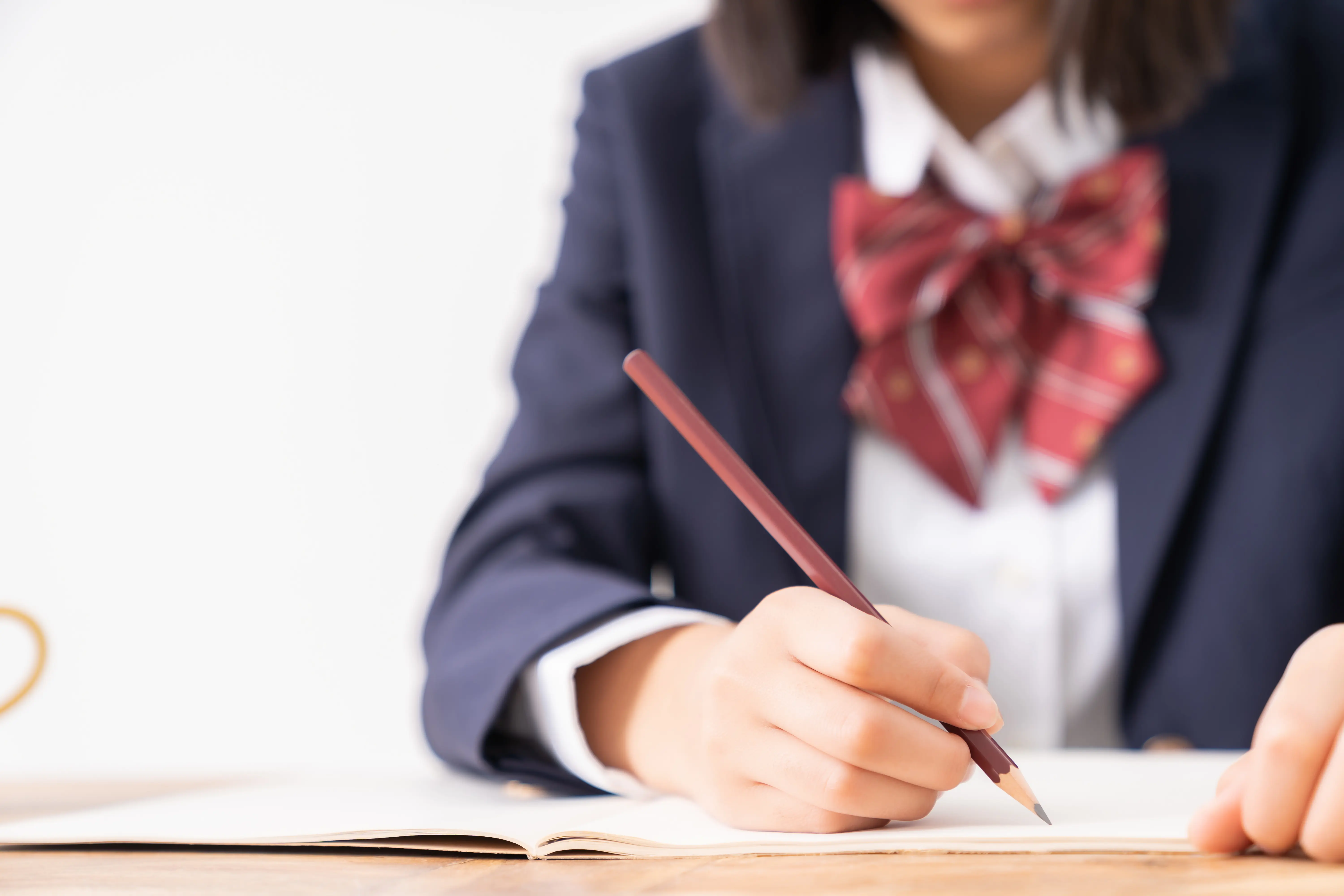 制服を着た学生が机で勉強している